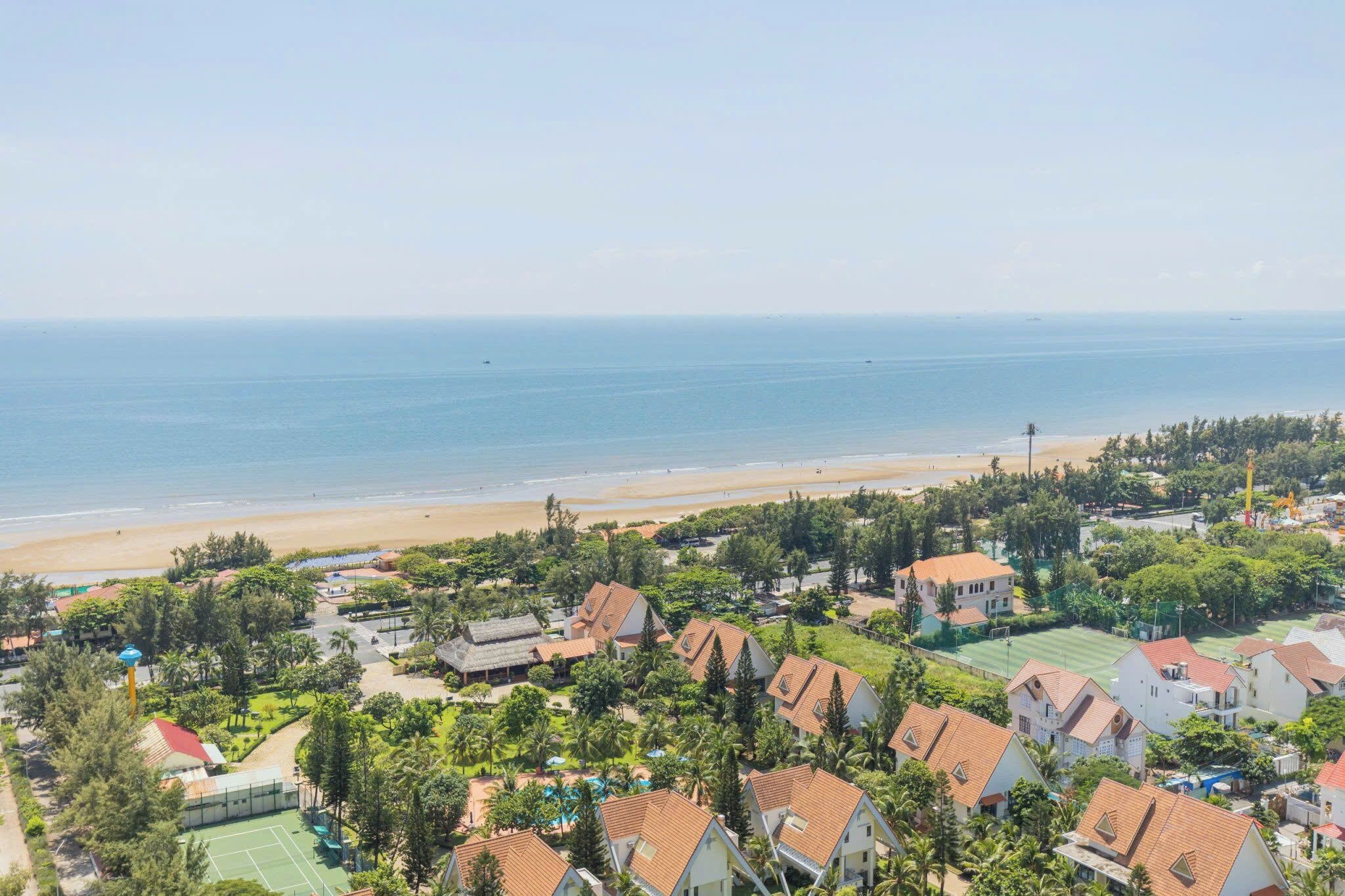 A coastal residential area with houses, a beach, and a clear view of the ocean.
