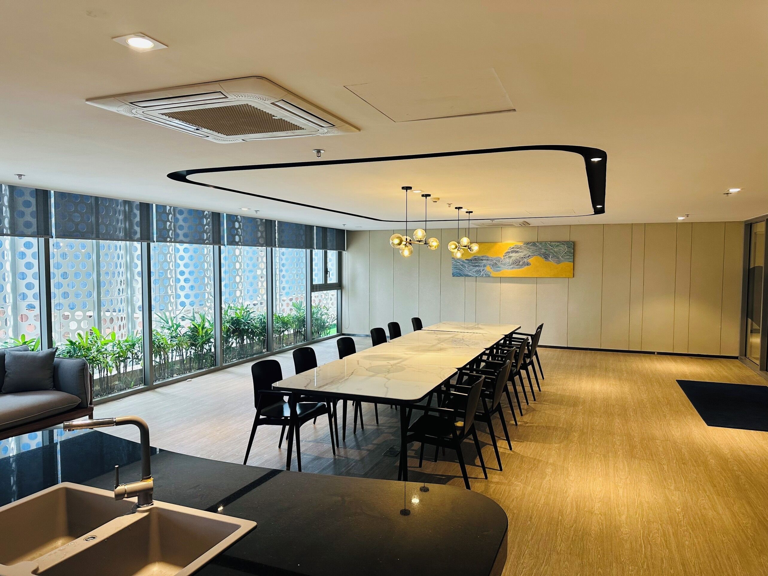 Una sala de conferencias moderna con una mesa larga, sillas negras, un ventanal con vistas y un techo de diseño único.
