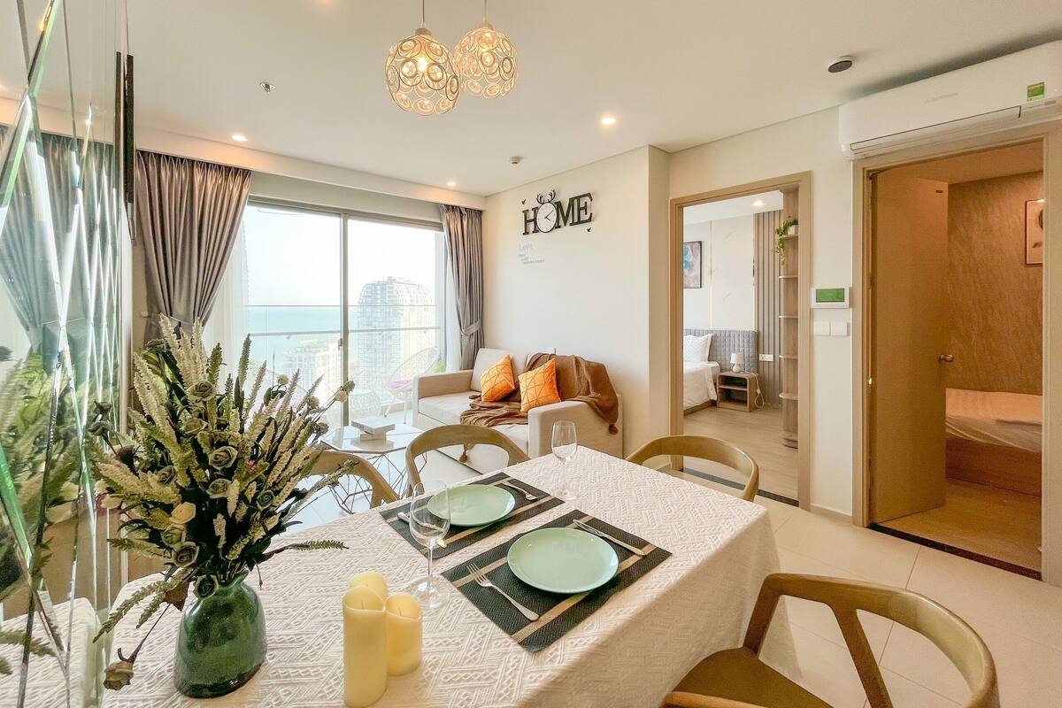 A modern living room with a dining area, large windows, and a view of the city.