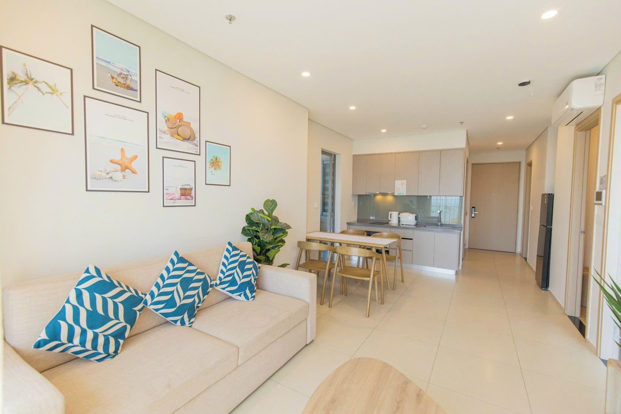 A modern living room with a sofa, a dining table, and a kitchen in the background.