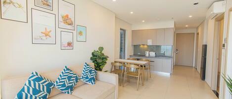 A modern living room with a sofa, a dining table, and a kitchen in the background.