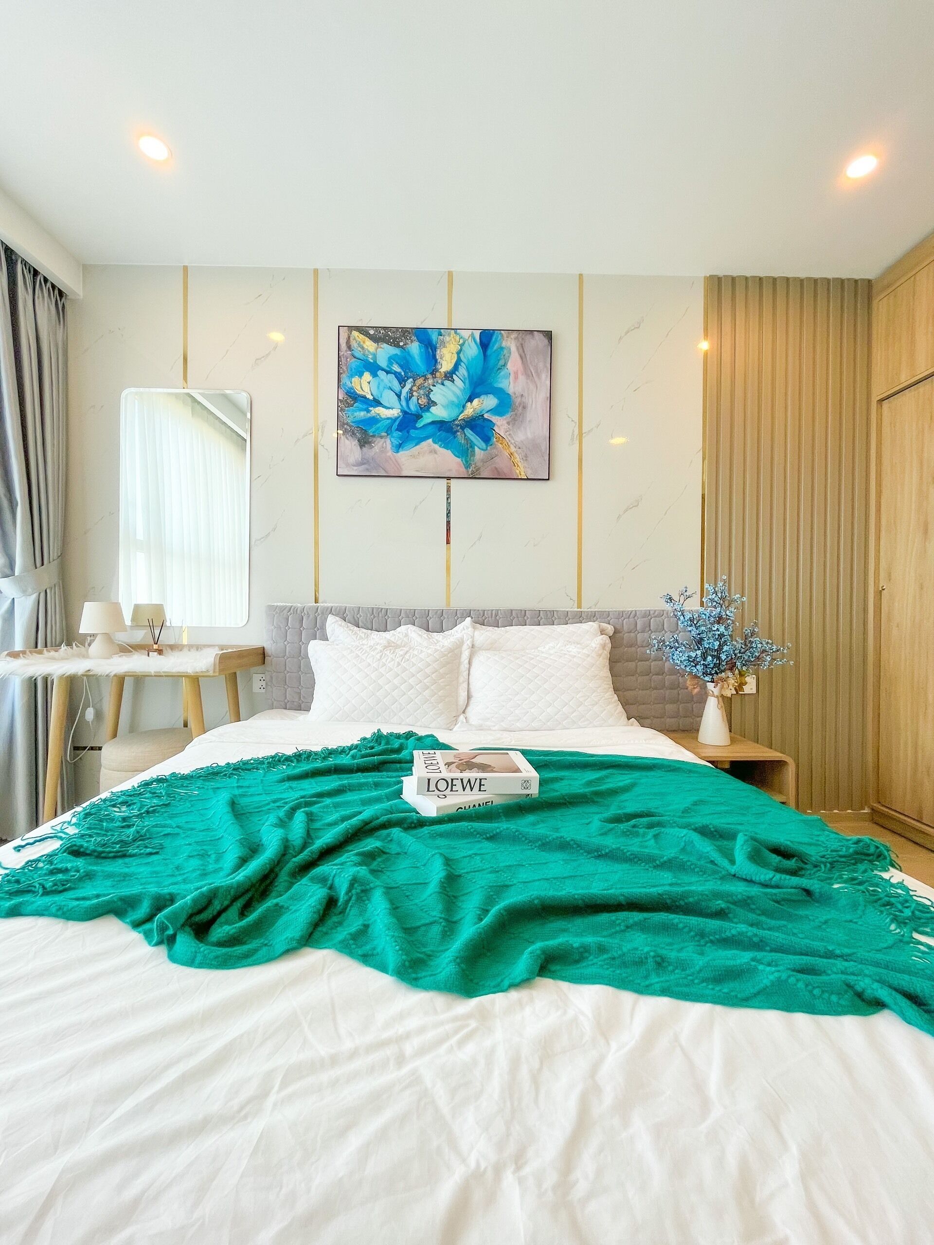 Quarto de hotel com cama, quadro na parede, mesa de cabeceira, abajur e janela com cortinas.