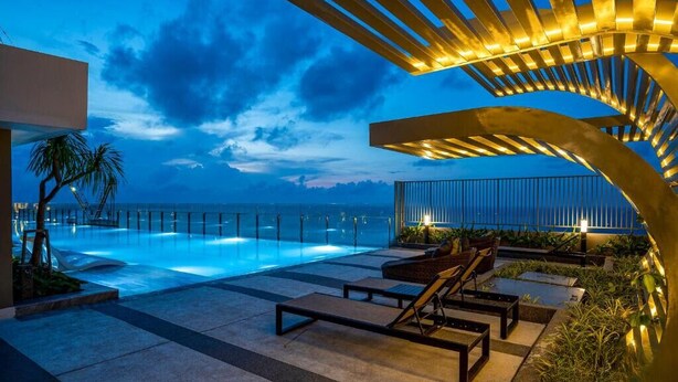 Ein moderner Poolbereich im Freien mit Liegestühlen und Blick auf das Meer im Abendrot.