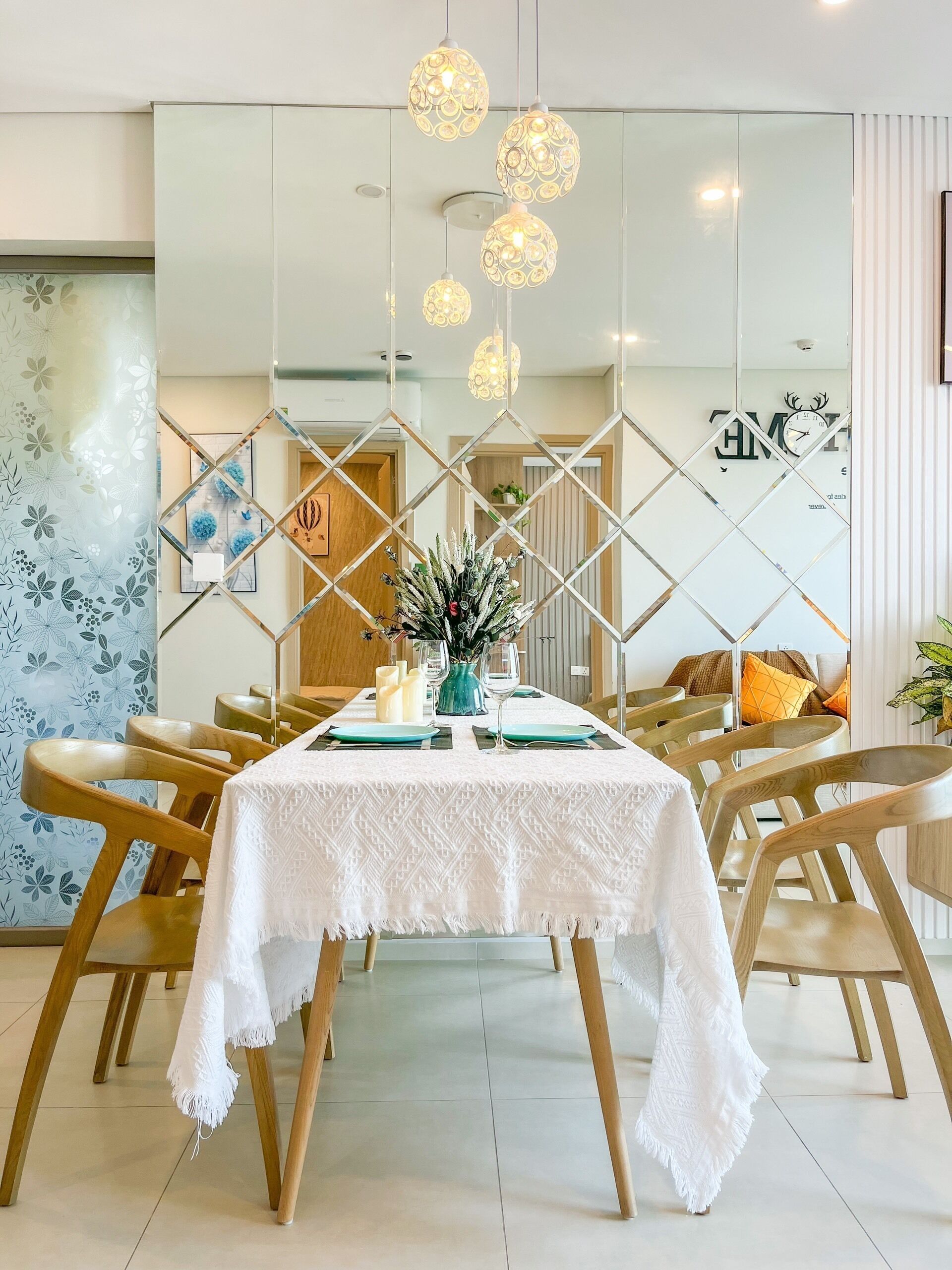 A dining area with a white tablecloth, wooden chairs, and hanging pendant lights.