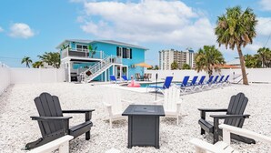 Un hôtel situé en bord de mer, avec un bâtiment bleu, des espaces de détente en plein air et une piscine.