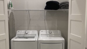 A laundry room with two stacked washers and dryers, a hanging light fixture, and a towel rack above the dryers. - Delightful 3-bedroom house in Bradenton with WiFi, Games, and more #1 of 2 (Bradenton)