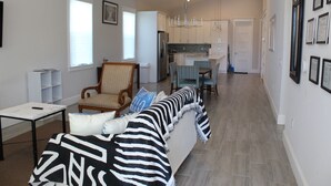 A modern living room with a sofa, a dining area, and a kitchen. - Delightful 3-bedroom house in Bradenton with WiFi, Games, and more #1 of 2 (Bradenton)