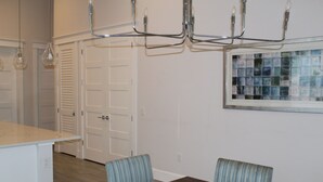 A dining area with a dark wooden table and two striped chairs, a chandelier, and a window with a mosaic. - Delightful 3-bedroom house in Bradenton with WiFi, Games, and more #1 of 2 (Bradenton)