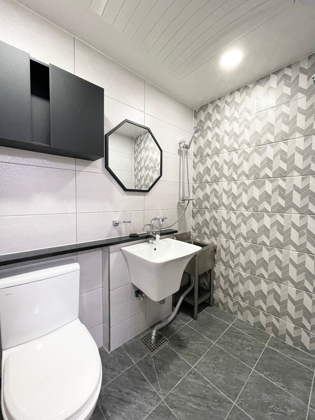 Une salle de bain moderne avec des toilettes blanches, un lavabo blanc et une douche.