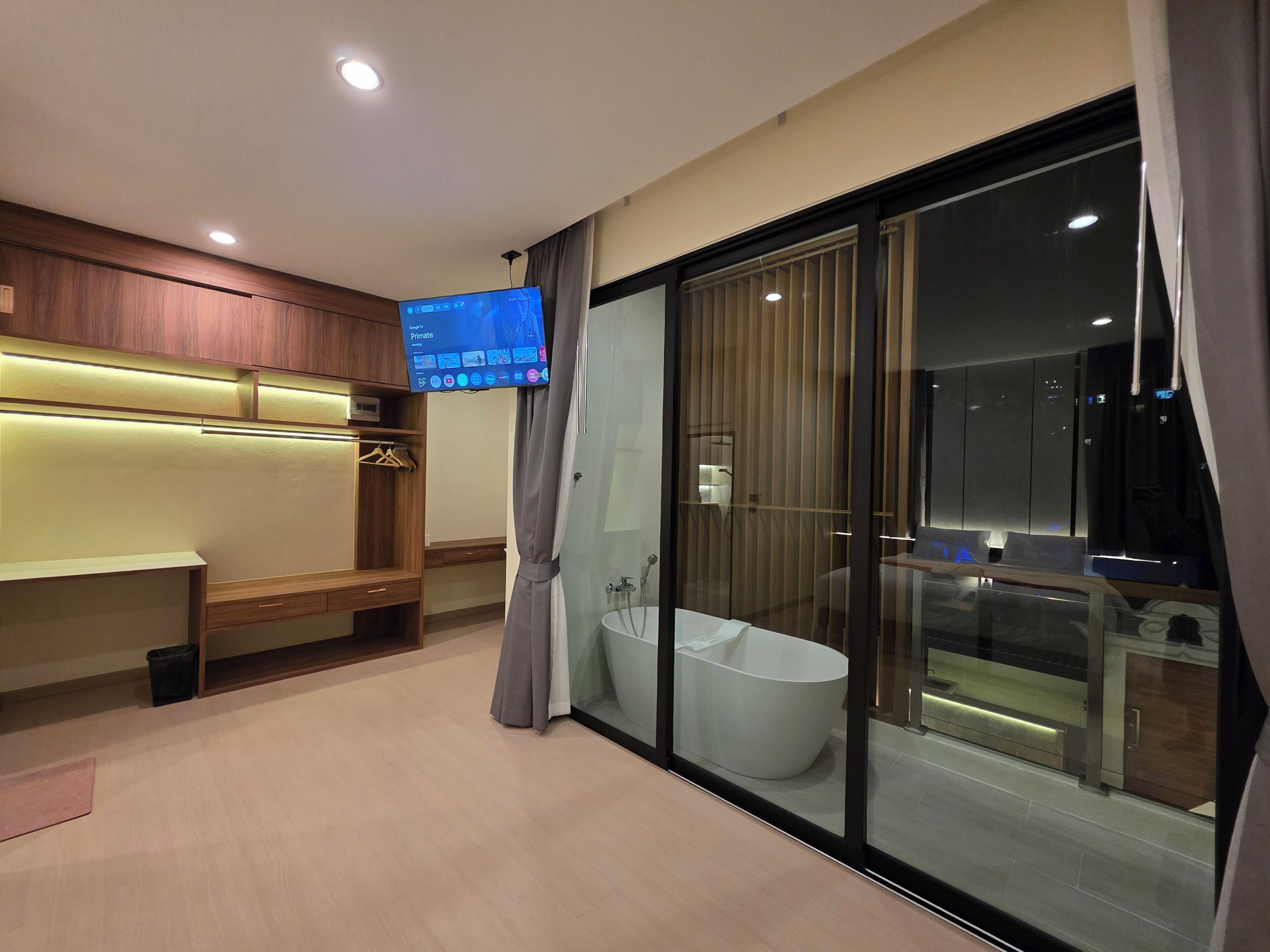Ein modernes Badezimmer mit einer Badewanne, einem Waschtisch inklusive Spiegel und einem an der Wand befestigten Fernseher.