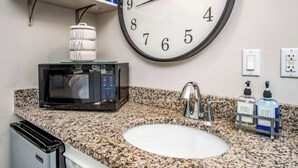 A kitchen with a granite countertop, a microwave, a sink, and a clock. - Honeymoon Banyan Suite near Higgs Beach (Key West)