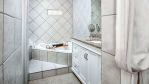 A modern bathroom with a freestanding bathtub, a vanity with a mirror, and a shower area. - Honeymoon Banyan Suite near Higgs Beach (Key West)