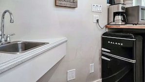 A kitchen with a stainless steel sink, a coffee maker, and a black Galanz refrigerator.