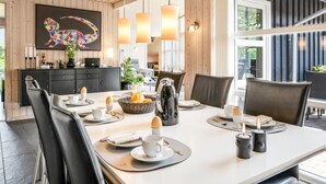 Un comedor moderno con techo de madera, un cuadro grande y vista al exterior.