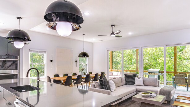 Une cuisine moderne dotée d’un îlot central, d’un coin repas avec des chaises et d’un espace de vie comprenant un canapé et une table basse.