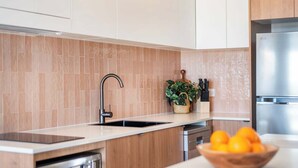 Une cuisine moderne équipée d’un lave-vaisselle encastré, d’un évier et d’un réfrigérateur en acier inoxydable.