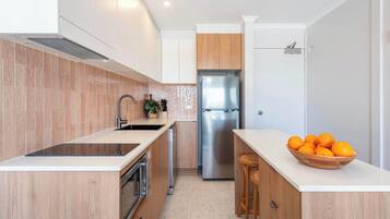 A modern kitchen with a stainless steel refrigerator, wooden cabinets, and a white countertop.