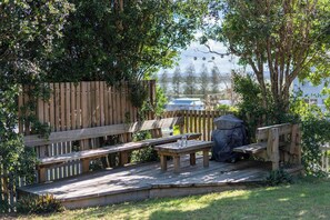 Una terraza de madera con bancos y una parrilla.