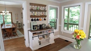 A kitchen with wooden cabinets, a coffee station, and a dining area with a table and chairs.
