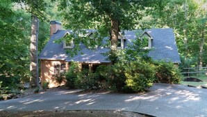 A house surrounded by trees with a driveway leading to the front door.