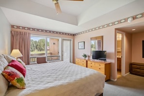 A bedroom with a bed, a TV, a dresser, and a balcony.