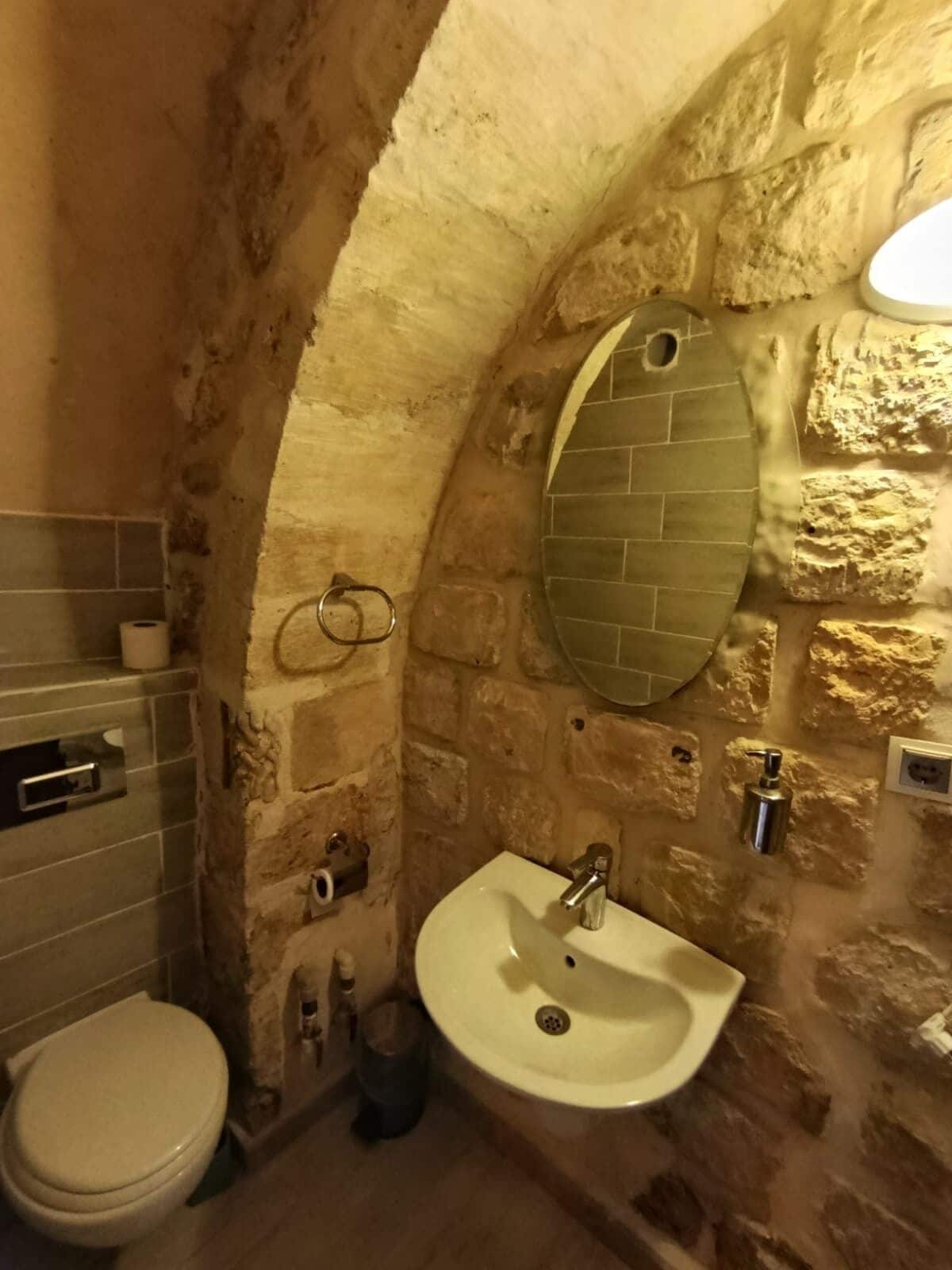 Un baño con un arco de piedra, un lavabo blanco y un inodoro.