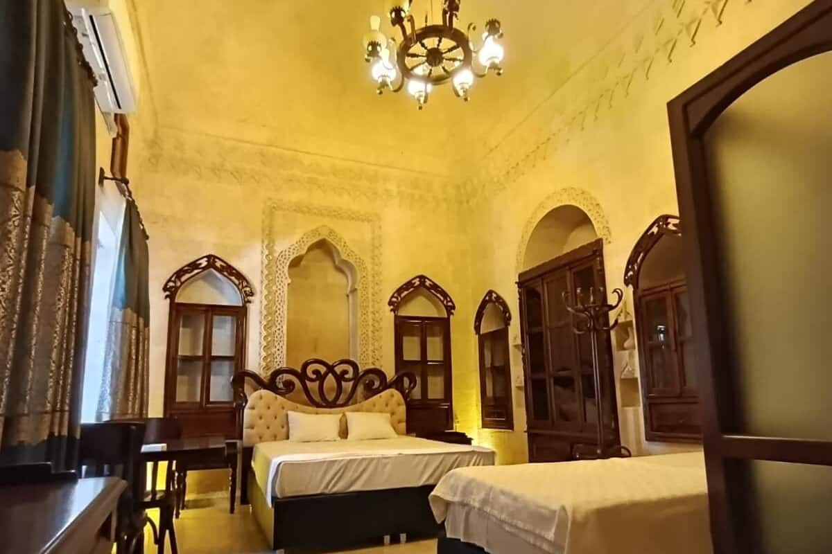 A traditional room with two beds, a chandelier, and ornate wooden furniture.