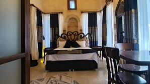 Une chambre à coucher avec un lit, un lustre, une table à manger avec des chaises et un tapis à motifs.
