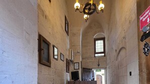 Un couloir étroit, avec un tapis rouge, un canapé marron et un lustre.