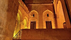 Un bâtiment historique doté d’arcades et d’un escalier menant à un balcon.