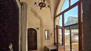 Une pièce dotée d’une grande fenêtre en arc de cercle, d’une porte en bois, d’un lustre et d’un tapis à motifs.