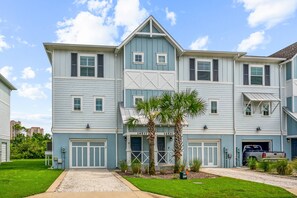 A two-story building with a garage and a driveway. - Private Beach Club| Two pools| Free Rounds of Golf| Free Community Shuttle| Tennis/Pickleball (Pensacola)