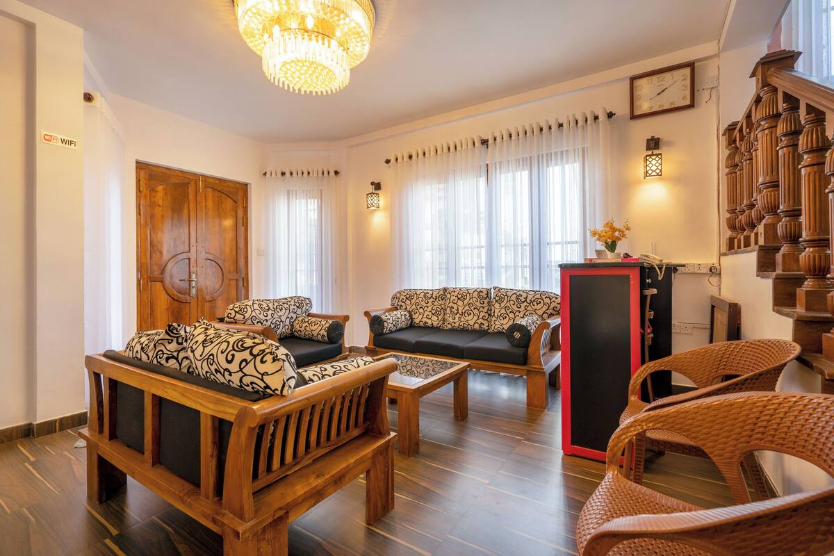 A spacious living room with wooden furniture, a chandelier, and a staircase.