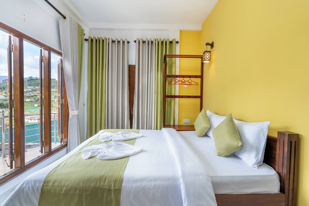A hotel room with a large bed, a view of the outdoors, and a wooden headboard.