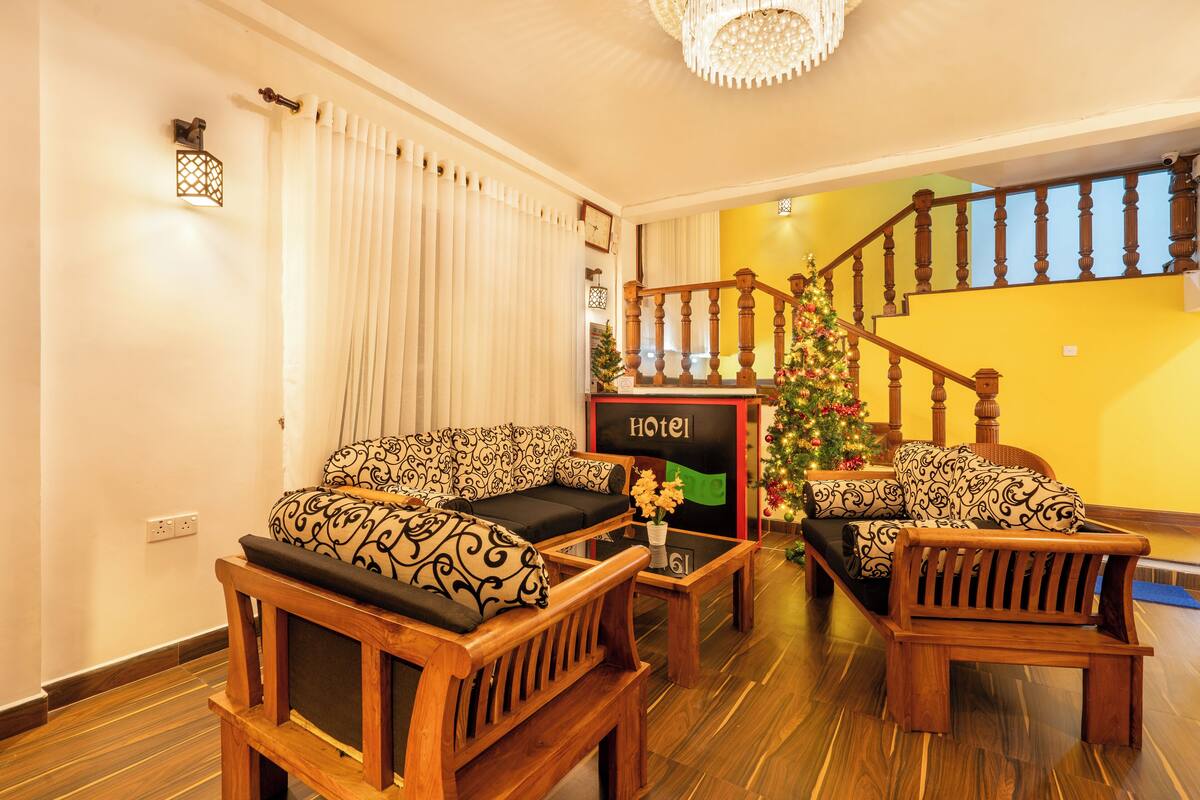 A hotel lobby with a staircase, wooden furniture, a Christmas tree, and a sign that reads "HOTEL".