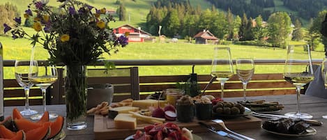 A table set with food and drinks, overlooking a mountainous landscape.
