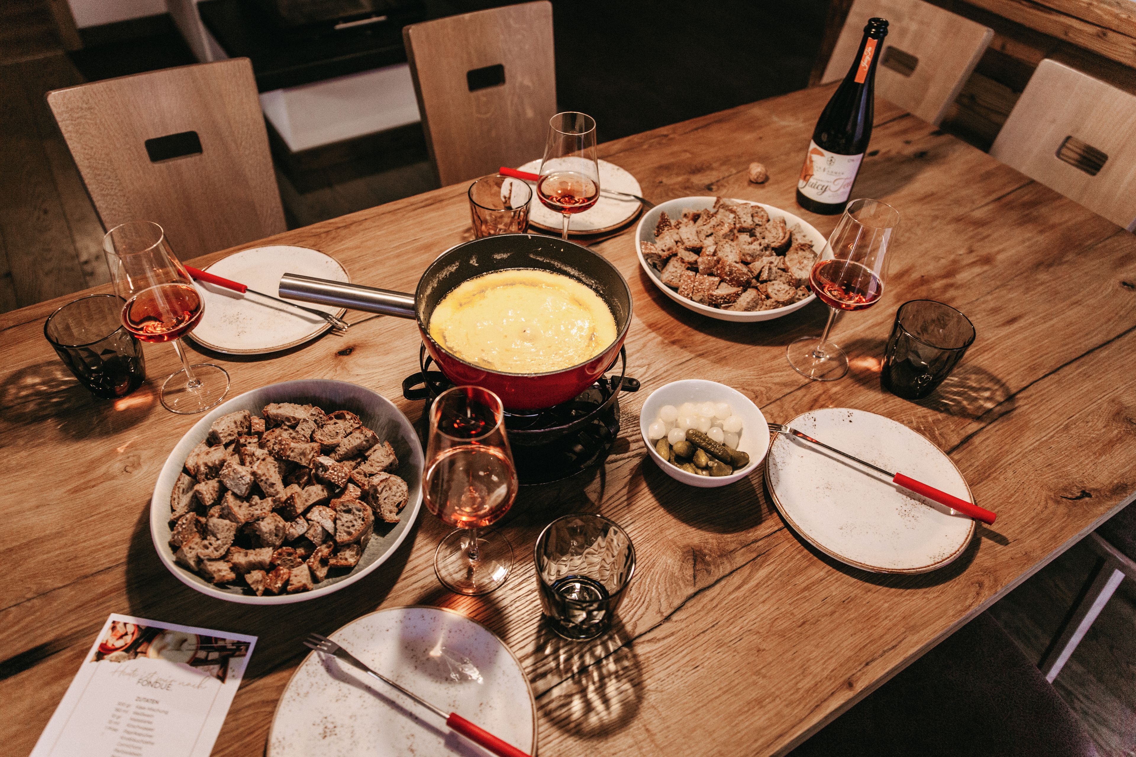 A dining table set with various dishes, glasses, and a bottle of wine.