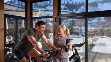 A gym with large windows, exercise bikes, and a water bottle.