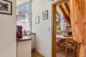 A kitchen with a wooden countertop, a red appliance, and a window with a view.