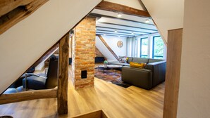 A loft-style room with exposed wooden beams, a brick wall, and a modern sofa. - Apartment 'Michels Mühle  - Pitt Sin Atelier' with Private Terrace, Private Garden and Wi-Fi (Brilon)