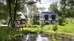 A house with a pond in front, surrounded by trees and grass. - Apartment 'Michels Mühle  - Pitt Sin Atelier' with Private Terrace, Private Garden and Wi-Fi (Brilon)