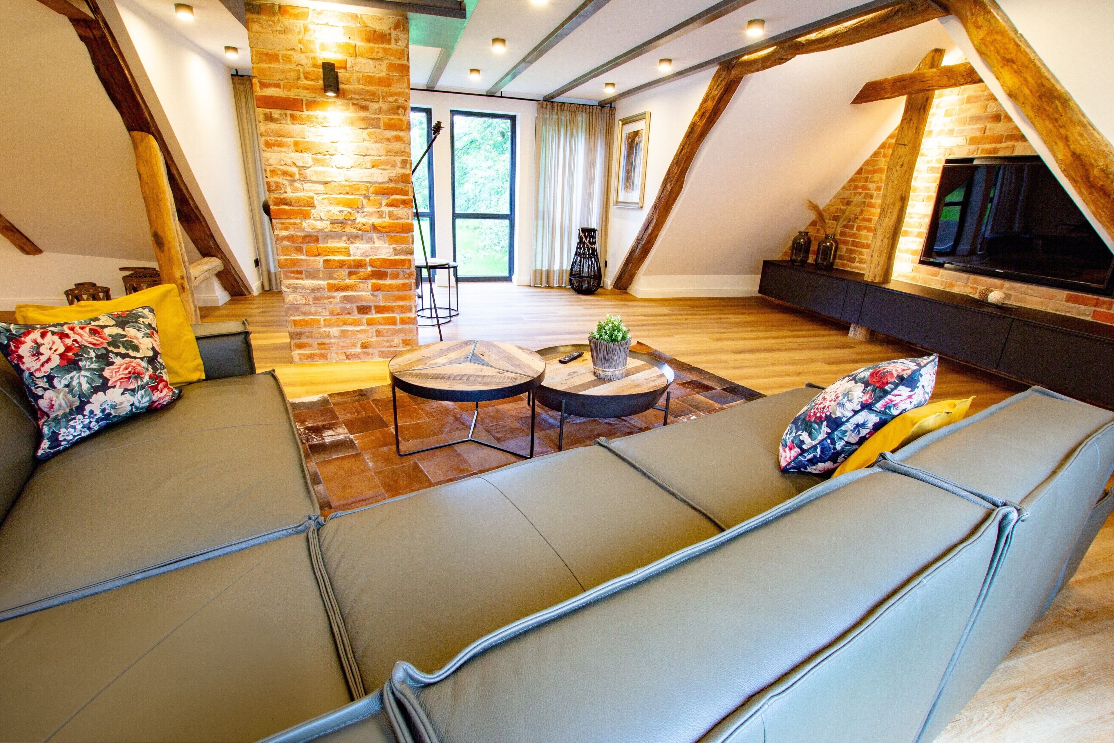 Ein Loft-Wohnzimmer mit Steinwand, einer Couch, einem Couchtisch und einem Fernseher.