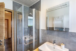Une salle de bain moderne avec une douche à parois de verre, un lavabo avec un miroir et un porte-serviettes.