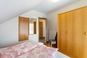 Quarto com cama, guarda-roupa, cadeira e espelho.