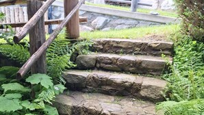 A set of stone steps leading up to a wooden staircase with metal railings, surrounded by greenery. - 'Adlerhütte' with Mountain View, Private Garden and Wi-Fi (Stieflberg)