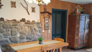 A wooden dining table with chairs, a stone wall, a wooden door, and a cabinet with floral designs. - 'Adlerhütte' with Mountain View, Private Garden and Wi-Fi (Stieflberg)