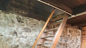 A wooden staircase leading to a loft area with a stone wall and a wooden platform. - 'Adlerhütte' with Mountain View, Private Garden and Wi-Fi (Stieflberg)