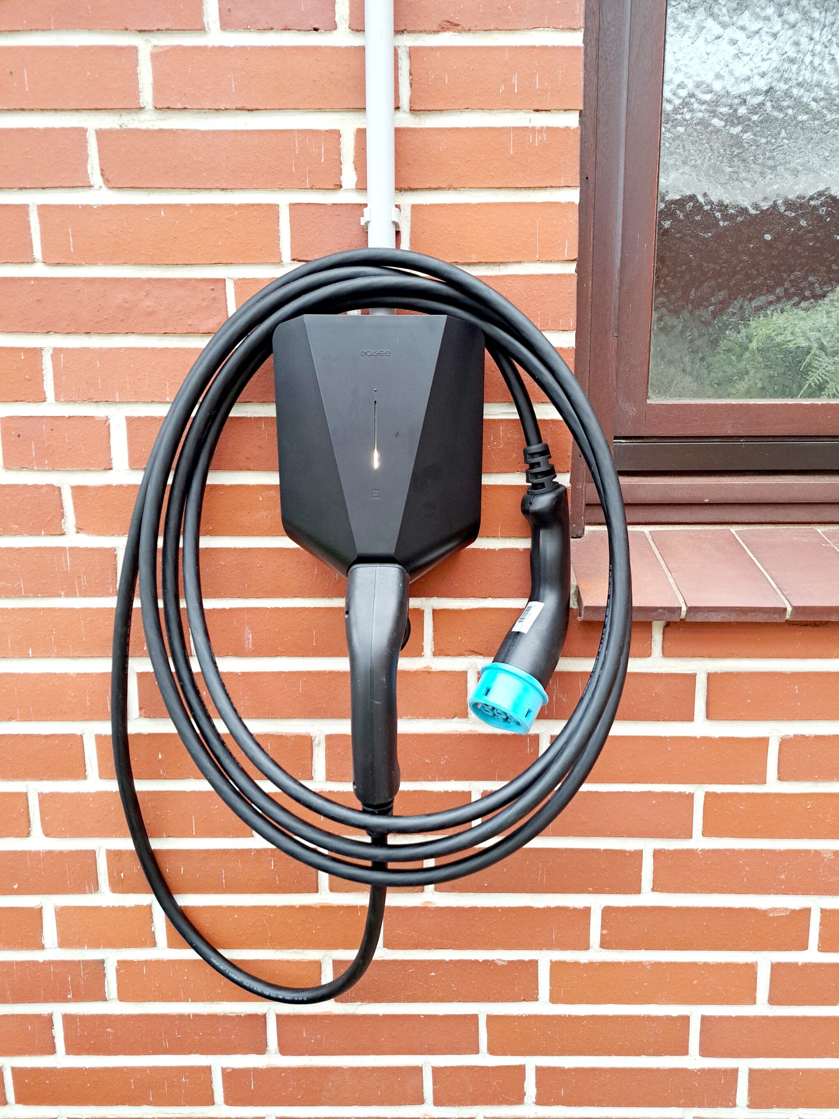 A black outdoor electrical outlet mounted on a brick wall.