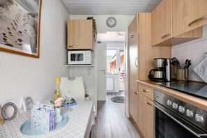 A kitchen with wooden cabinets, a microwave, a stove, and a dining area with a table set for two.
