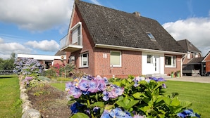 Een huis met twee verdiepingen, met een bakstenen gevel, een schuin dak en het cijfer '18' op de voorgevel.